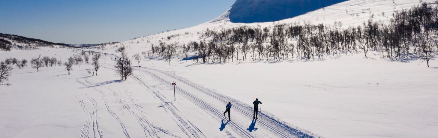 Två personer åker längdskidor på fjället