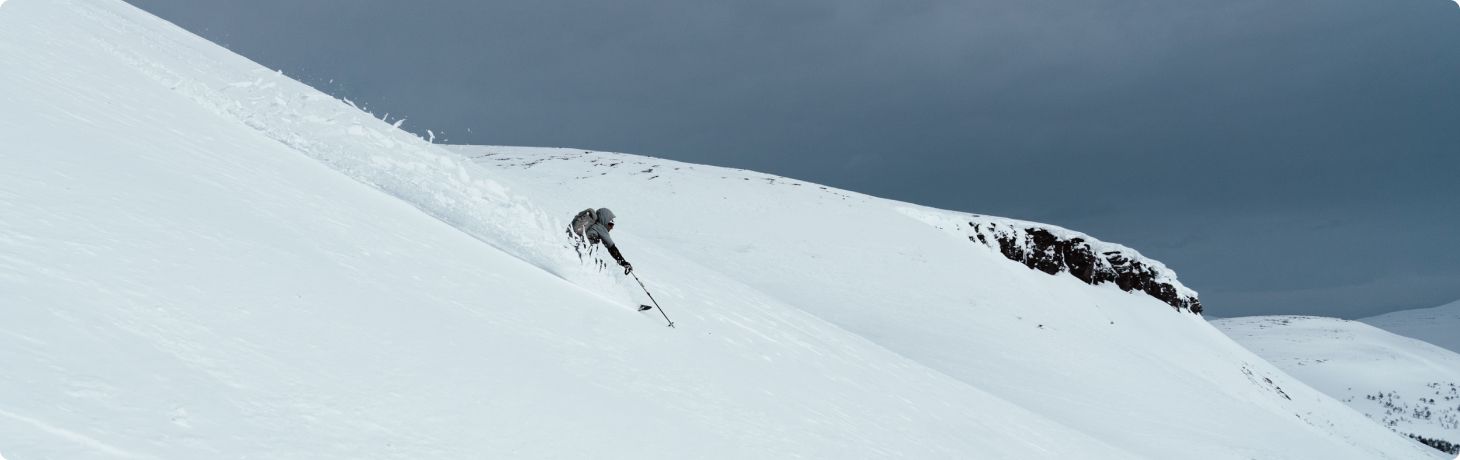 Man åker skidor nedför ett berg i lössnö