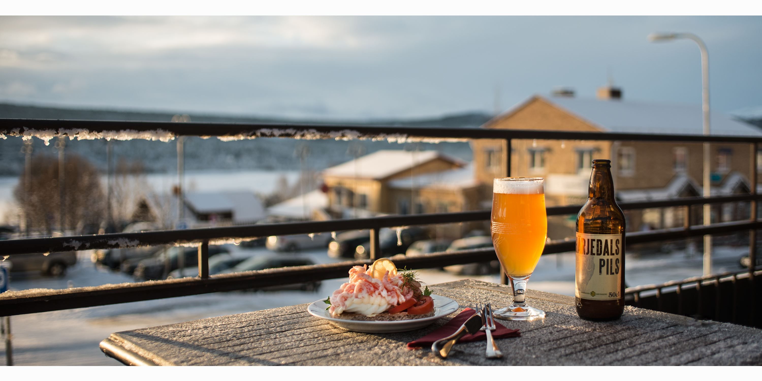 En räksmörgås och ett glas öl på uteservering med utsikt över Funäsdalssjön