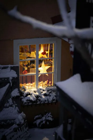 Fönster från en stuga med en julstjärna i fjällmiljö