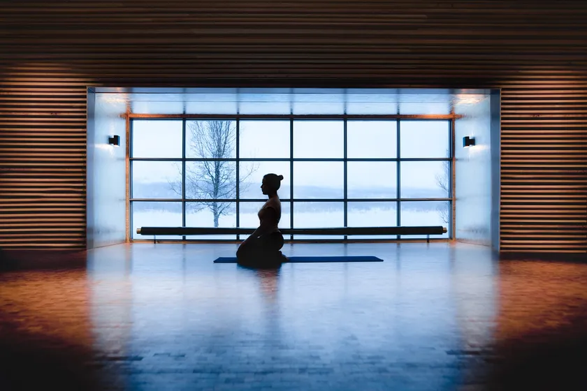 Person som sitter på yogamatta framför ett stort fönster med utsikt.
