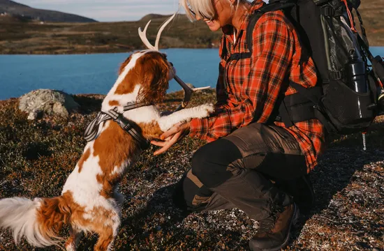 Kvinna leker med sin hund på en vandring