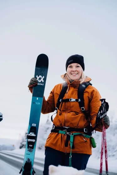 Kvinna står med skidor i vintern