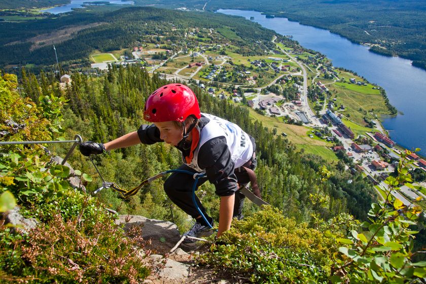 Pojke klättrar med guide uppför ett berg