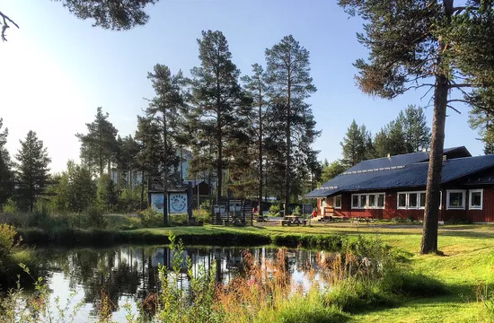 Liten damm med skog runt om och Tännäs Fiskecentrum i bakgrunden.