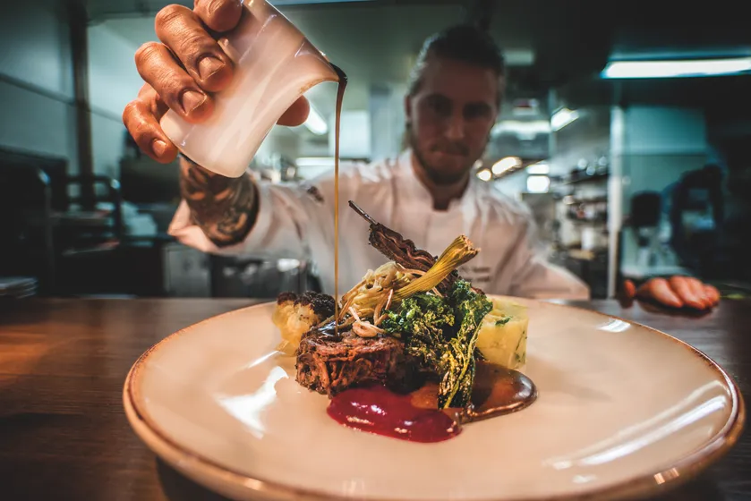 Man häller upp sås på en tallrik på en restaurang